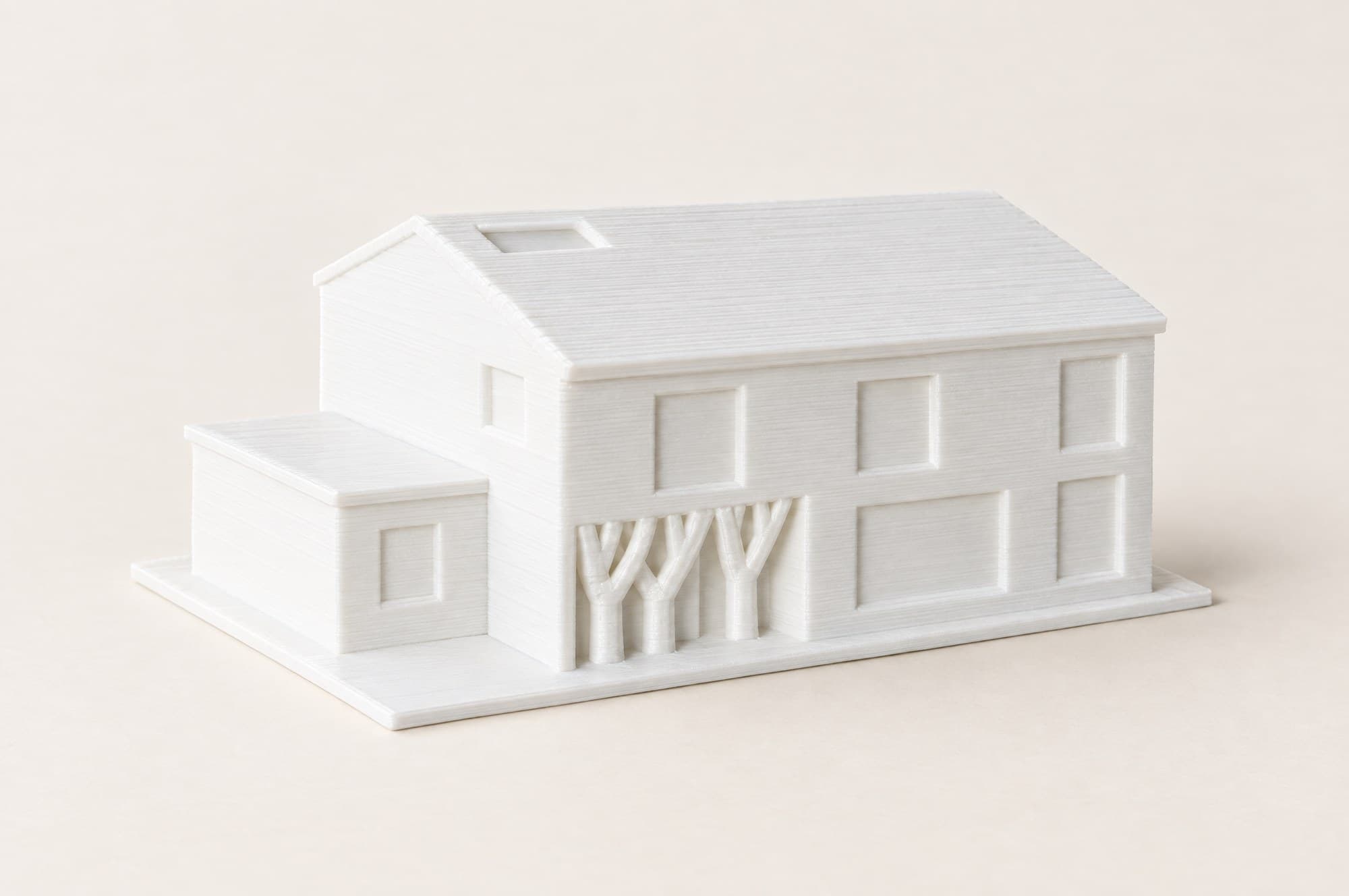 Weißes 3D-gedrucktes Architekturmodell auf hellem Papier, von schräg oben.
